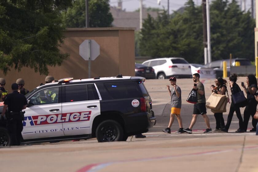 People raise their hands as they leave a shopping center following reports of a shooting, Saturday, May 6, 2023, in Allen, Texas. (AP Photo/LM Otero)