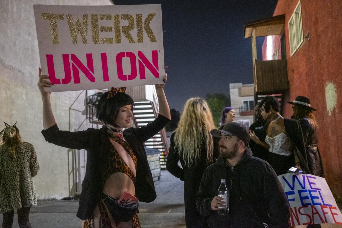 A woman holds a sign that says "Twerk Union" with others nearby.
