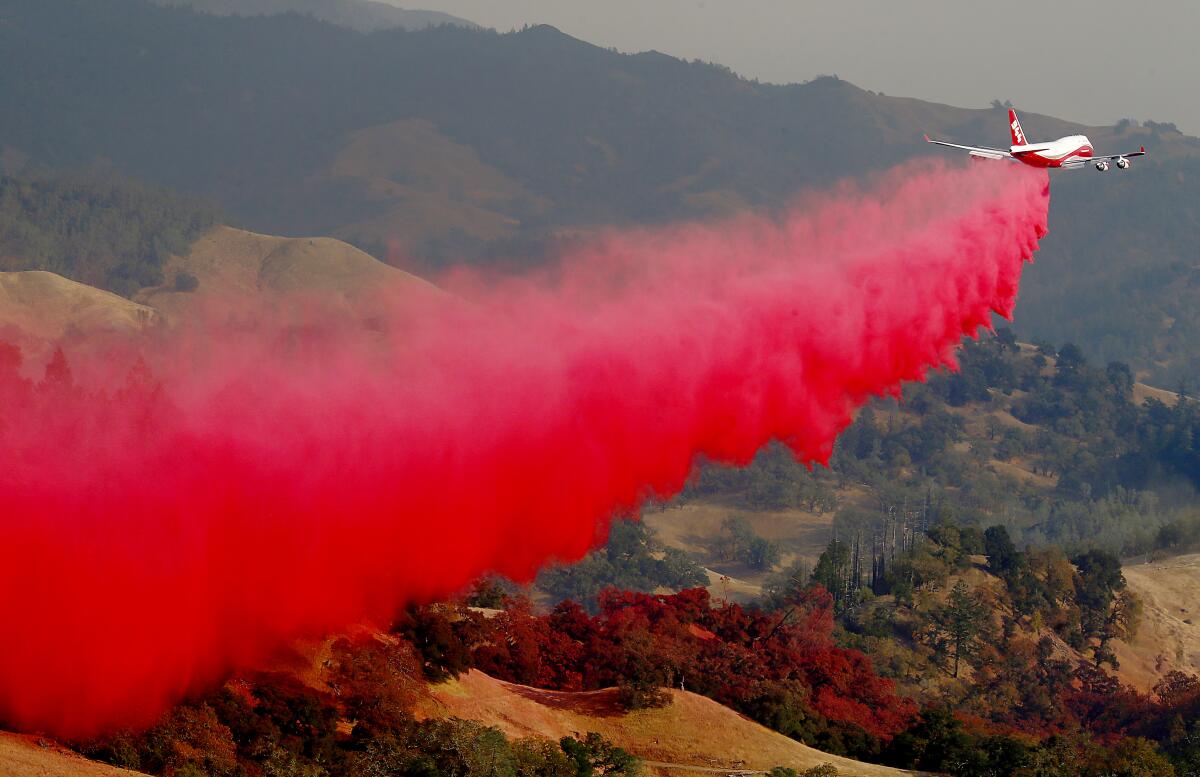 A tanker drops bright-red retardant over a wildfire in Sonoma County