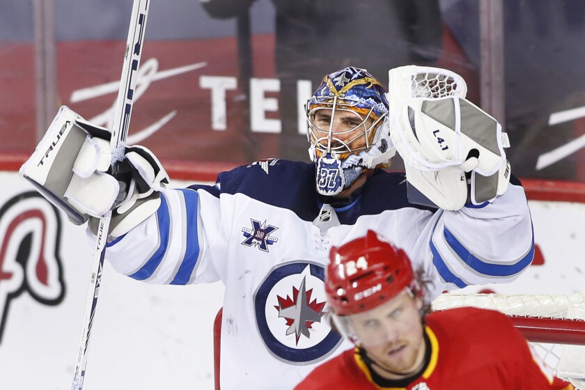Winnipeg Jets goalie Connor Hellebuyc celebrates the team's 4-0 win as Calgary Flames' Brett Ritchie skates past, at the end of an NHL hockey game Wednesday, May 5, 2021, in Calgary, Alberta. (Larry MacDougal/The Canadian Press via AP)