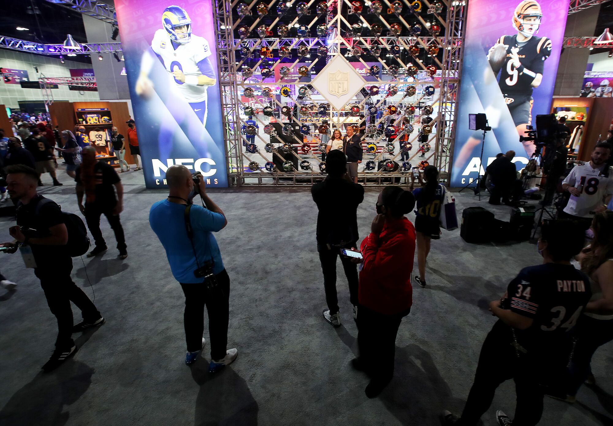 Fans take in a display of the football helmets of every team in the NFL at the Super Bowl Experience.