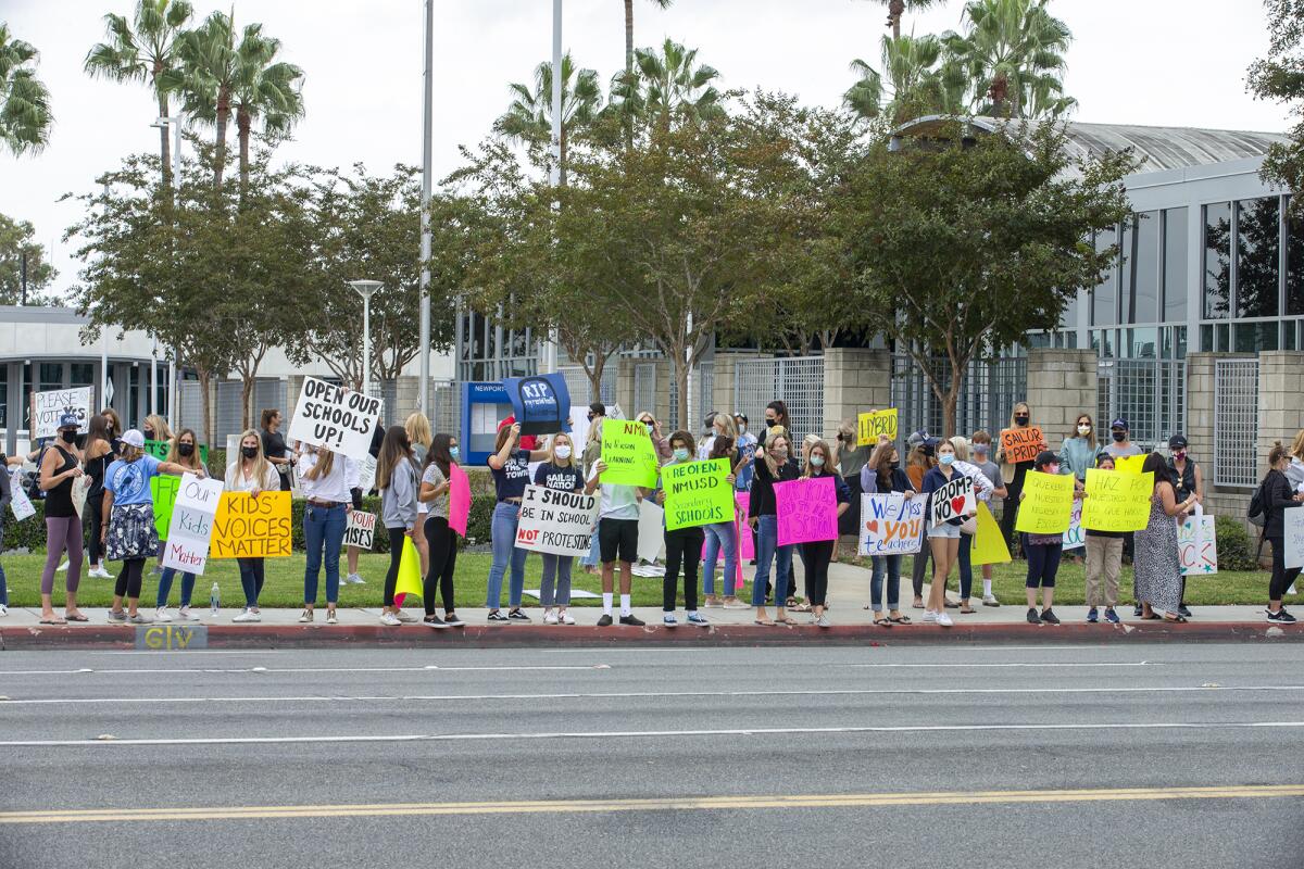 Parents and students line up on the sidewalk and protest outside the Newport-Mesa Unified School District office.
