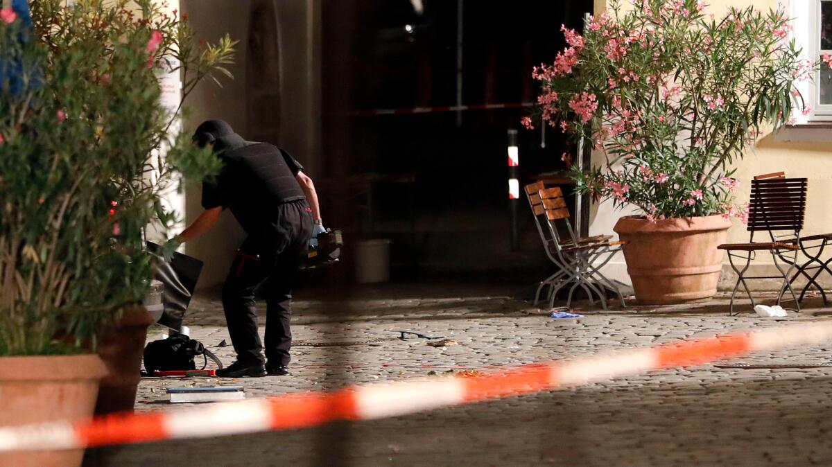 Police examine a backpack at the entrance of a building in Ansbach, Germany. Bavaria's top security official says a man who blew himself up after being turned away from an open-air music festival in the southern German city was a 27-year-old Syrian who had been denied asylum.