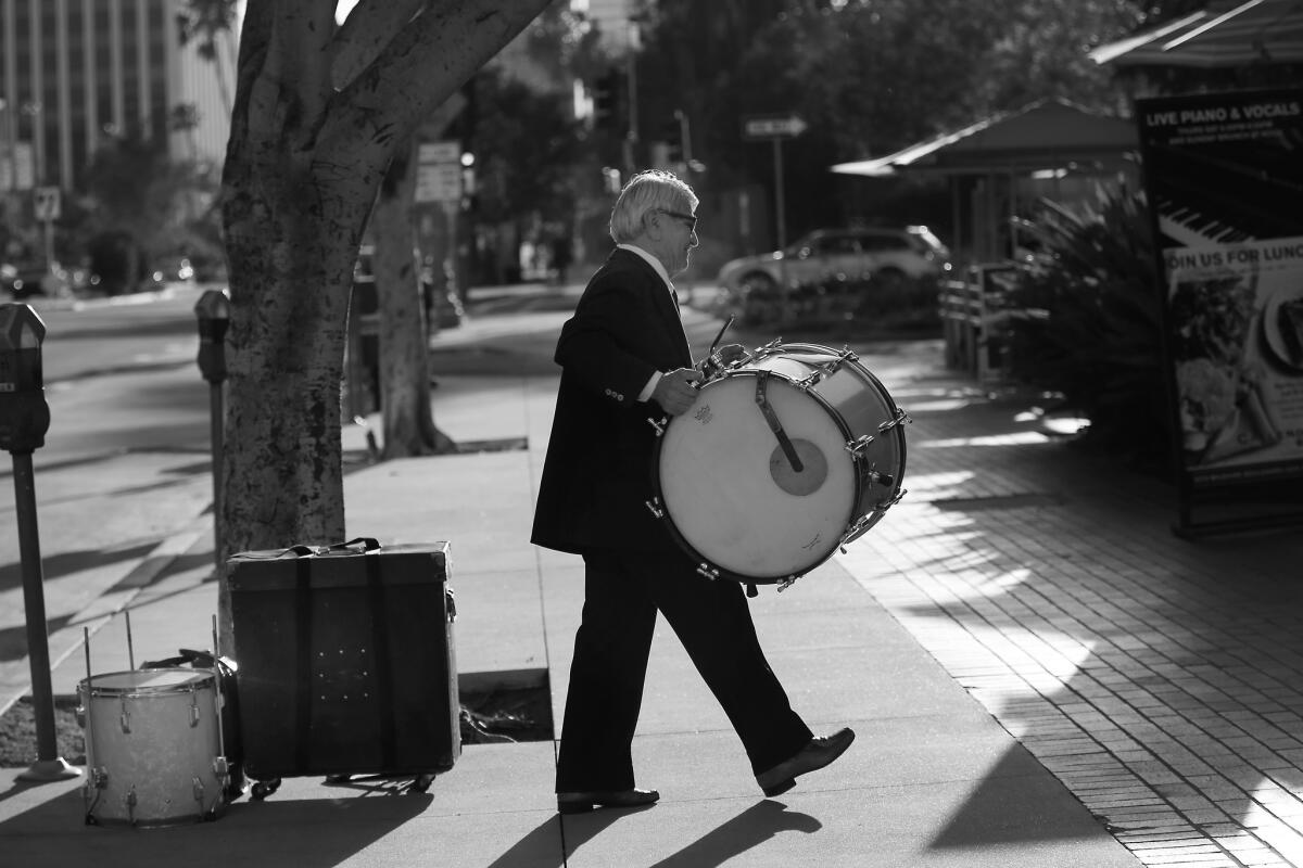 Wearing a suit and tie Steve Hideg, 85, carries his drums into Callender's Grill before his gig in Los Angeles.