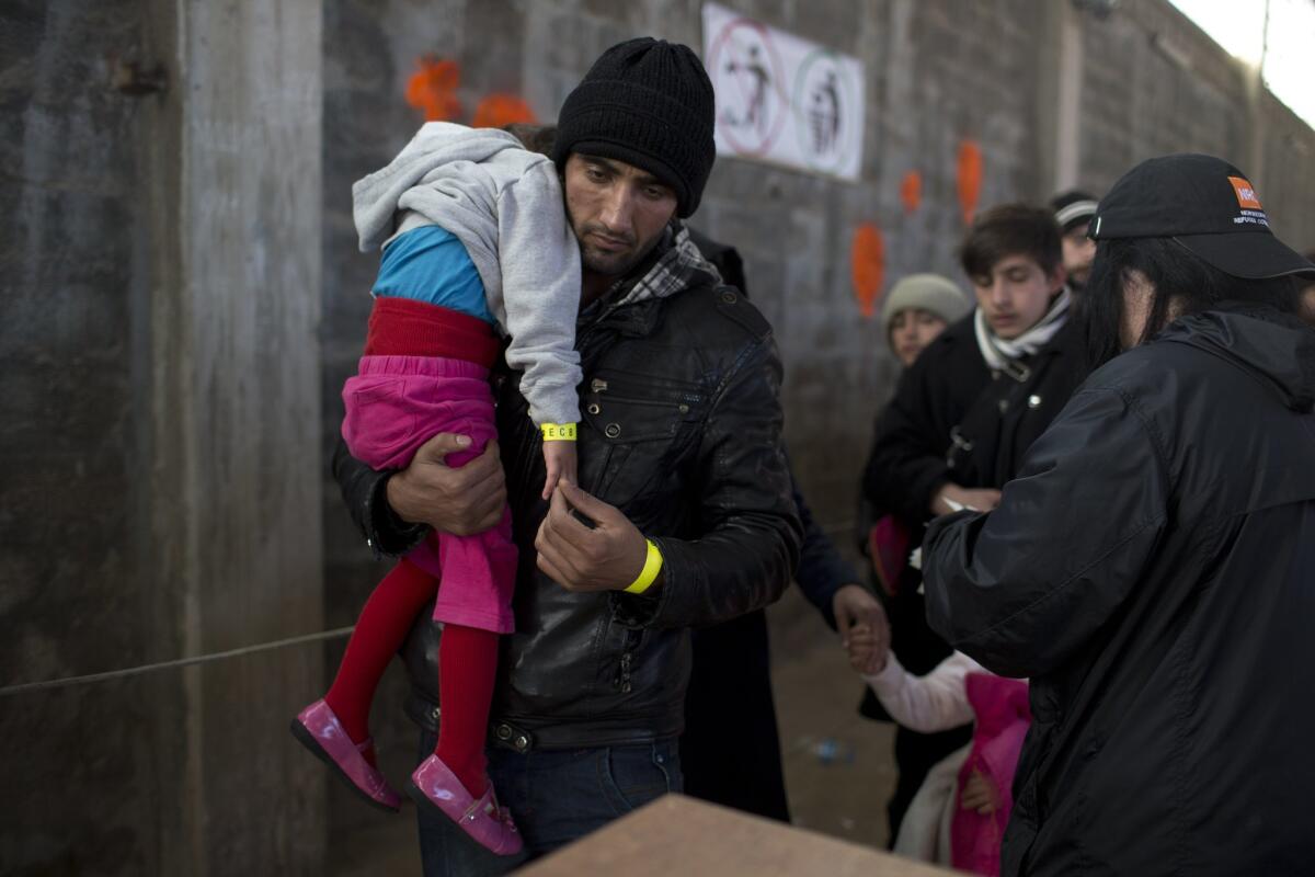 An Afghan man and his daughter receive wristband tags at Tabakika registration center, located on Chios Island in Greece, on Jan. 15.