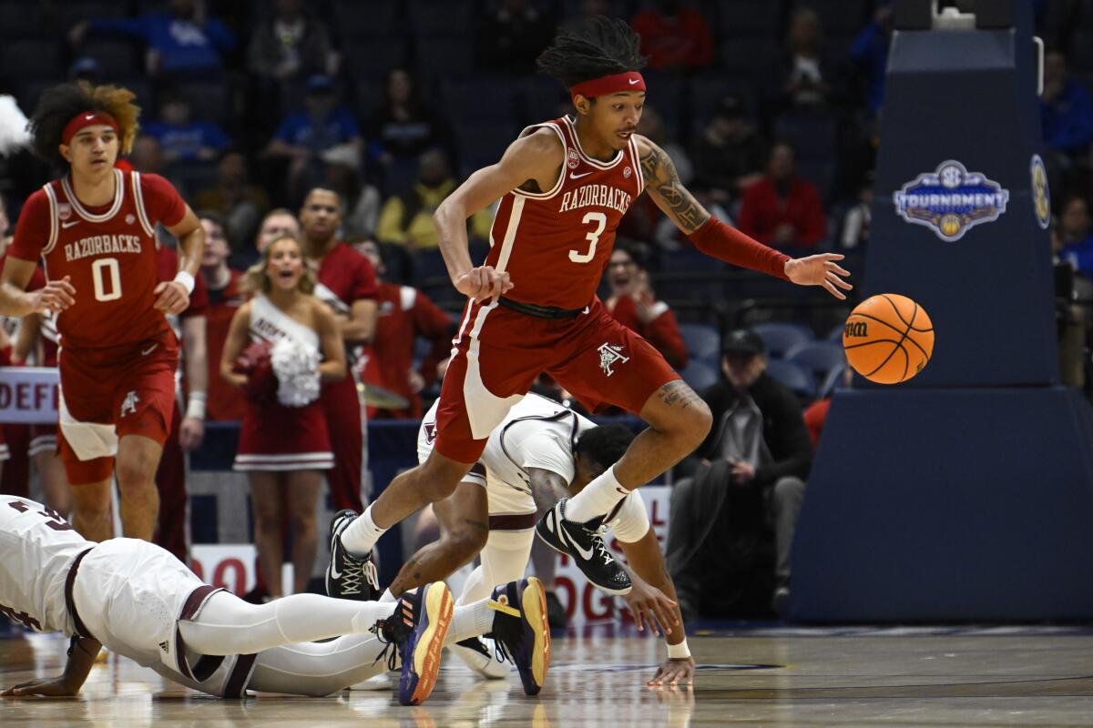 Arkansas guard Nick Smith Jr. jumps over Texas A&M forward Julius Marble to chase the ball.