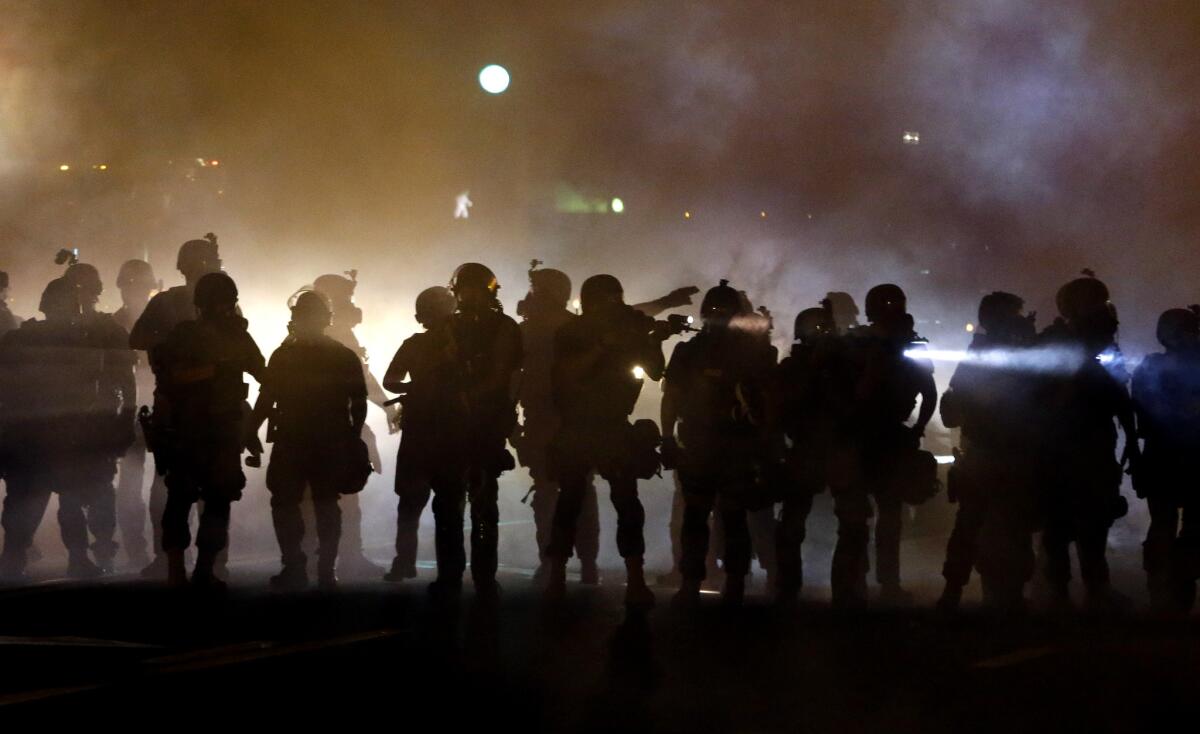 Police walk through a cloud of smoke Aug. 13 as they clash with protesters in Ferguson, Mo.