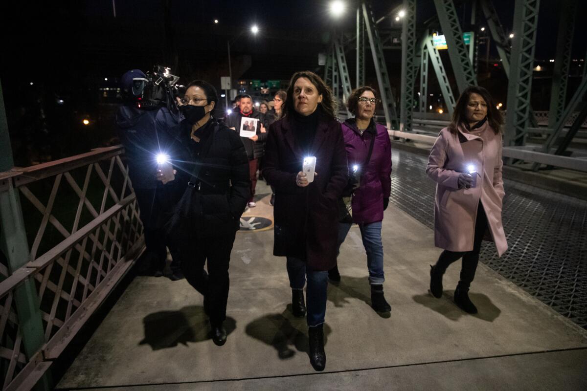In a photo provided by Multnomah County, Multnomah County Chair Deborah Kafoury, center, leads the illuminated walk over the Hawthorne Bridge with Commissioners Lori Stegmann, left, Jessica Vega Pederson, second from right, and Susheela Jayapal, right, Thursday, March 10, 2022, in Portland, Ore., during an event held two years after the first confirmed case of COVID-19 in Portland. (Motoya Nakamura/Multnomah County via AP)