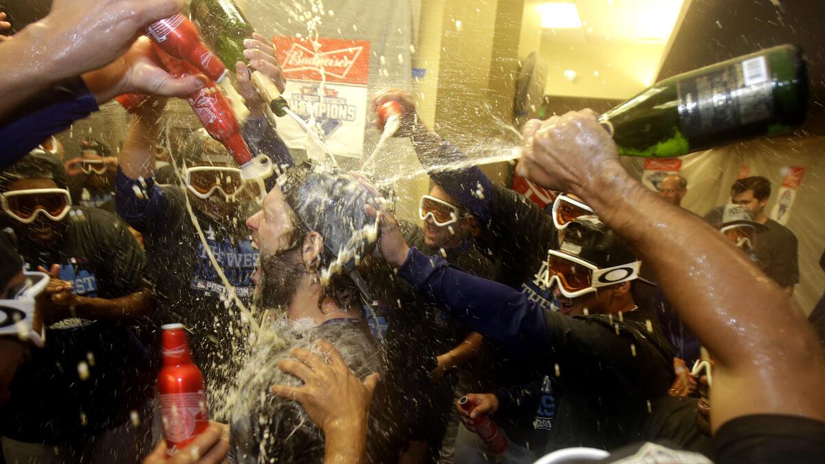 Pitcher Clayton Kershaw, center, is doused by teammates in the locker room after the Dodgers clinched the NL West title with an 8-0 victory over the Giants on Tuedsay in San Francisco.