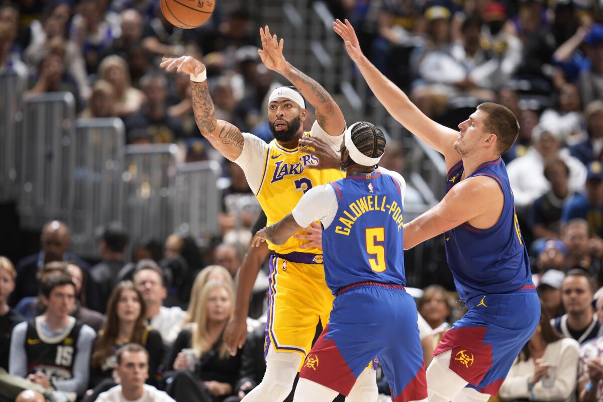 Lakers forward Anthony Davis passes the ball as Denver Nuggets guard Kentavious Caldwell-Pope and center Nikola Jokic defend.