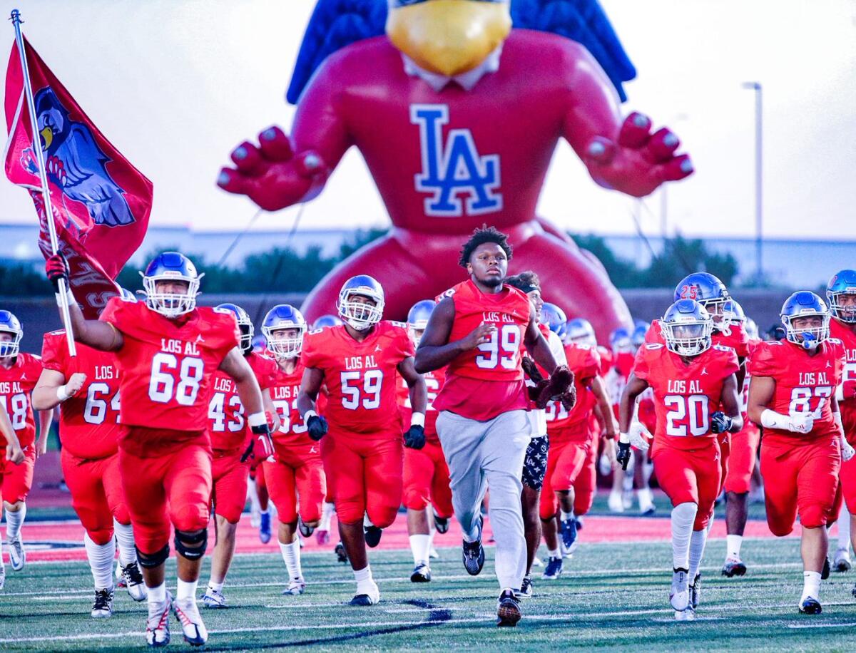 Ineligible T.A. Cunningham (99) leads out Los Alamitos on Thursday night against Santa Margarita.
