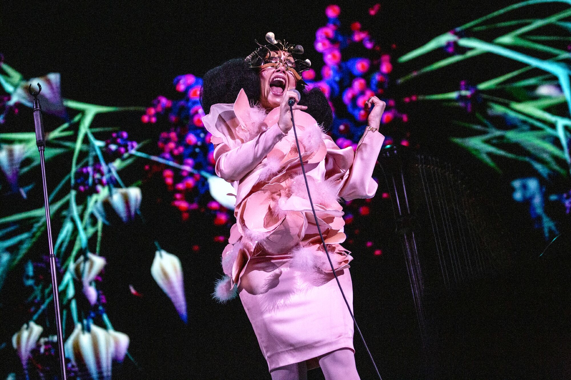 A woman in pink sings into a microphone.
