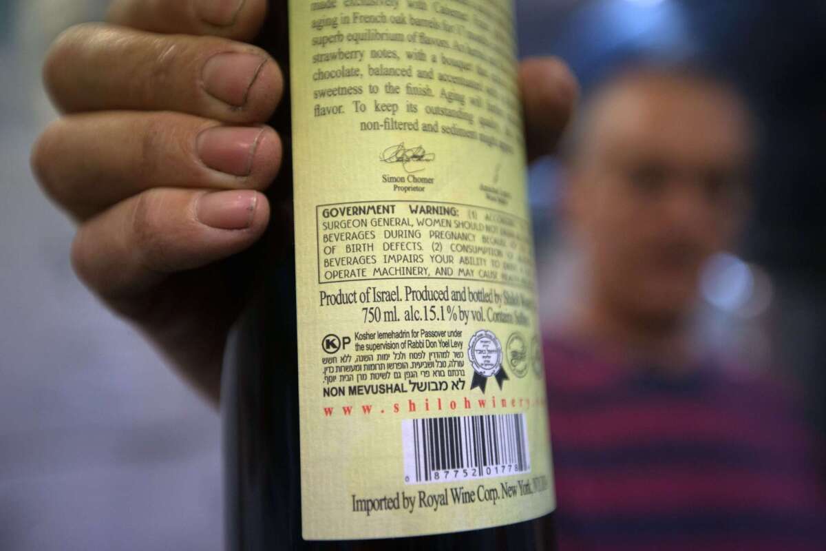 Amichai Luria presents a bottle of his wine, used mainly for export, at the Shilo winery in the Jewish settlement of Shilo in the West Bank on Nov. 12.