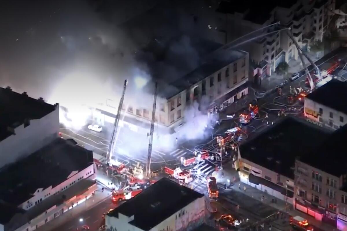 Aerial view of firetrucks outside a downtown building with smoke and flames