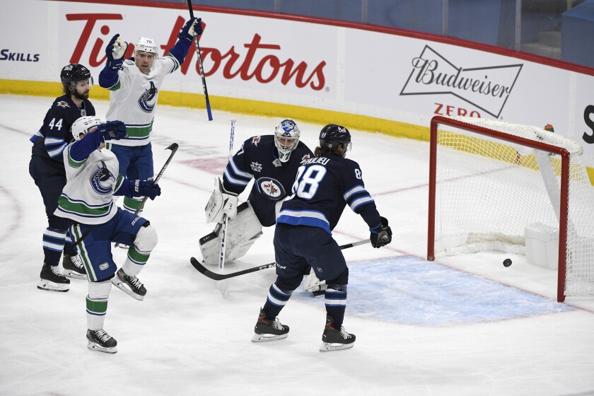 Vancouver Canucks' Nils Hoglander (36) celebrates his goal in front of Winnipeg Jets goaltender Connor Hellebuyck (37) during first period NHL hockey action in Winnipeg, Manitoba on Tuesday March 1, 2021. (Fred Greenslade/The Canadian Press via AP)