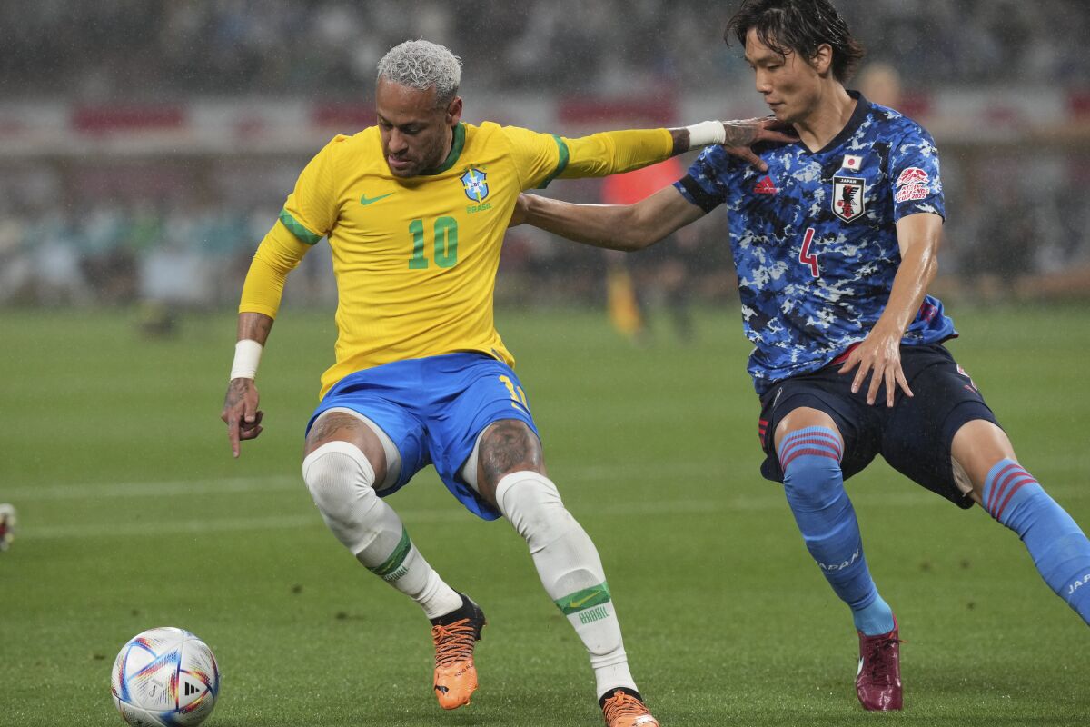 Neymar of Brazil, left, fights for the ball against Kou Itakura of Japan during a friendly match at the National Stadium in Tokyo Monday, June 6, 2022. (AP Photo/Eugene Hoshiko)