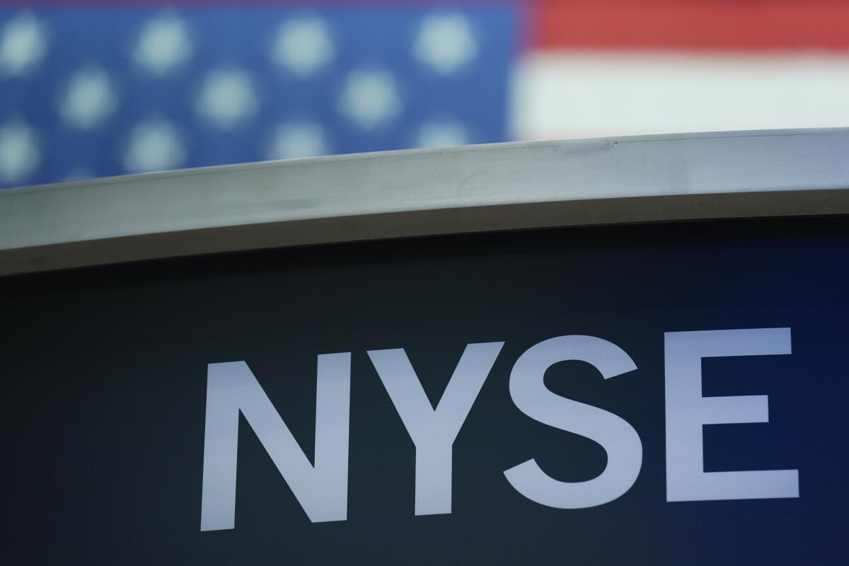 A New York Stock Exchange sign is displayed on the exchange's floor in front of a U.S. flag