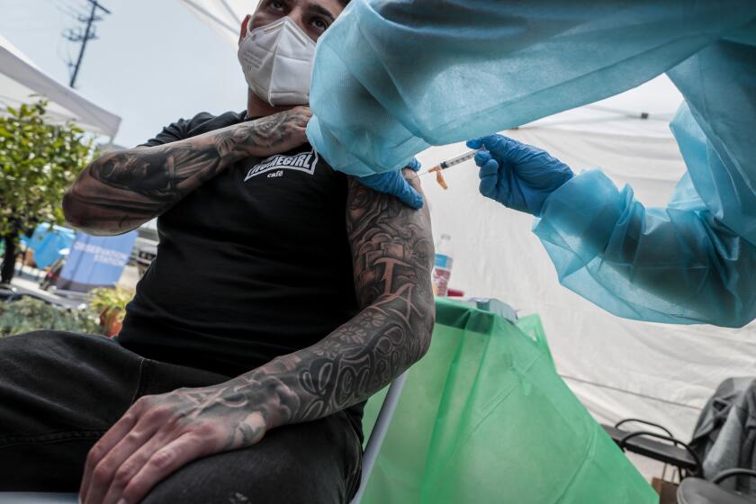 Los Angeles, CA, Wednesday, April 7, 2021 - Homeboy employee Hector Rodriguez recieves a shot from Greg Aralar. Shared Harvest, myCovidMD and VAXEQUITY partnered to host the COVID-19 clinic at Homeboy Industries downtown. VAXEQUITY techs delivered the second Moderna vaccine dose to Homeboy Industries personnel who received their first dose in March. Johnson & Johnson single-dose vaccine was also delivered to eligible community members. (Robert Gauthier/Los Angeles Times)