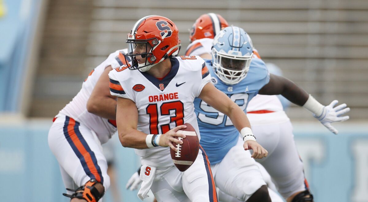 FILE - Syracuse quarterback Tommy DeVito (13) scrambles to avoid North Carolina defender Jahlil Taylor (52) in first half of an NCAA college football game in Chapel Hill, N.C., in this Saturday, Sept. 12, 2020, file photo. Syracuse success will depend on a defense that finished 112th overall in 2020, and an offense that struggled behind two-year starter Tommy DeVito, who missed much of last season with an injury.(Robert Willett/The News & Observer via AP, Pool, File)