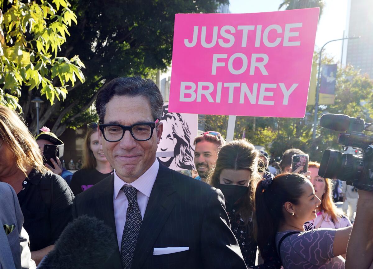 A lawyer smiles in front of a sign that reads "Justice for Britney."