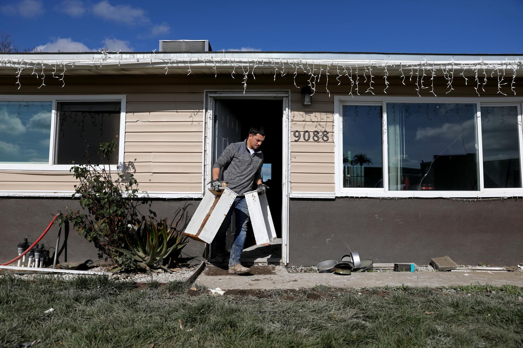 Mike Hurtado removes flood-damaged cabinets at his home along Stanford Avenue in Planada, Calif.