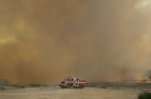 A lone fire crew checks the approaching works the wildfire as it approaches the Diamond R ranch in Mira Loma.