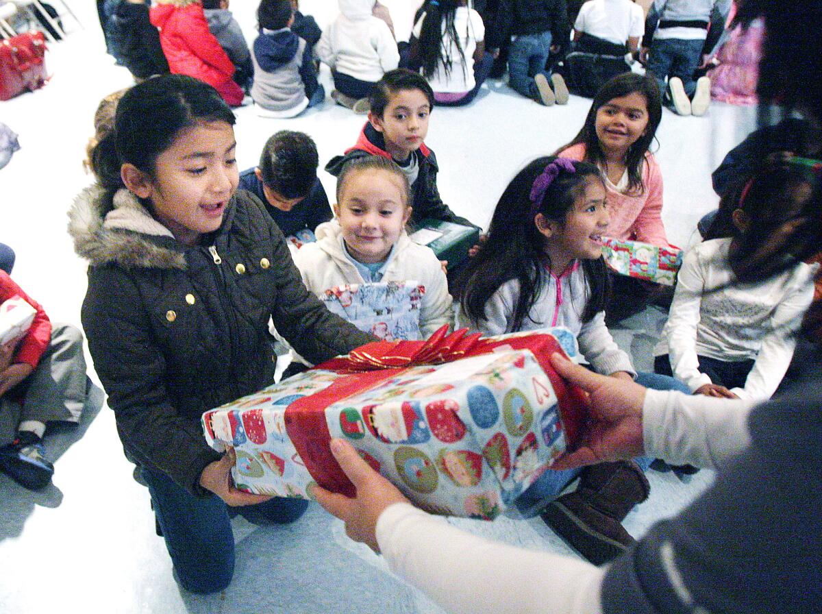 Ayleen Palacios, 6, receives a gift at Cerritos Elementary School on Monday, Dec. 14, 2015. The staff of Dignity Health Glendale Memorial Hospital and Health Center, which is across the street from the school, picked names and bought gifts for each of the 439 students at the school.