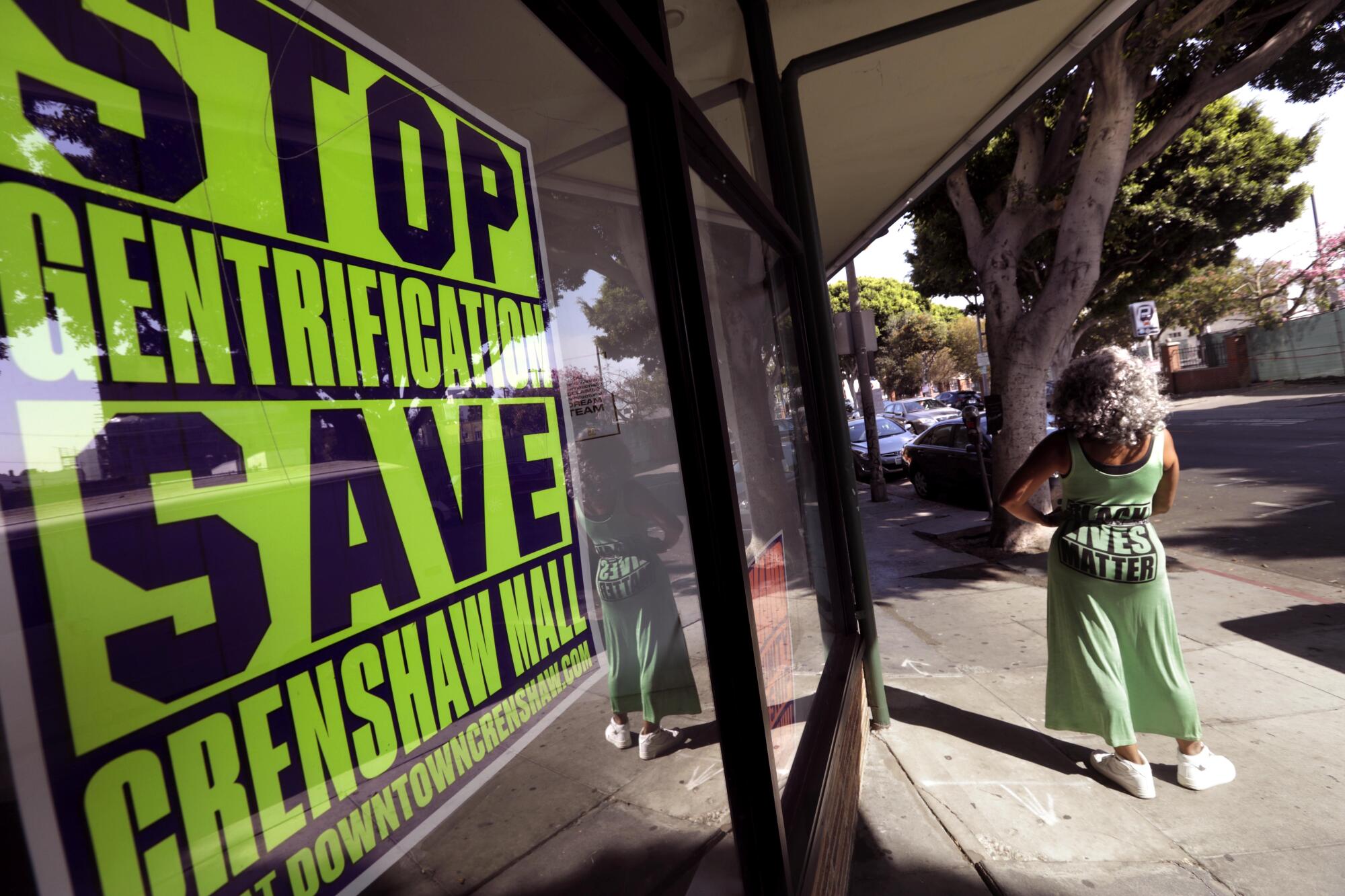 Kim Maxwell stands next to a "Stop Gentrification" sign