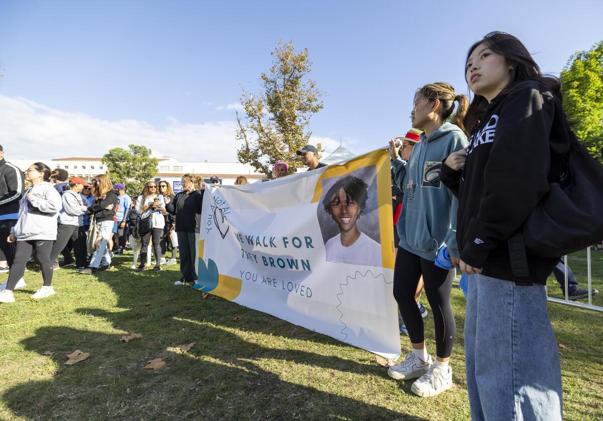 People hold up a poster with an image of a teen with dark hair and the words Walk for Trey Brown 