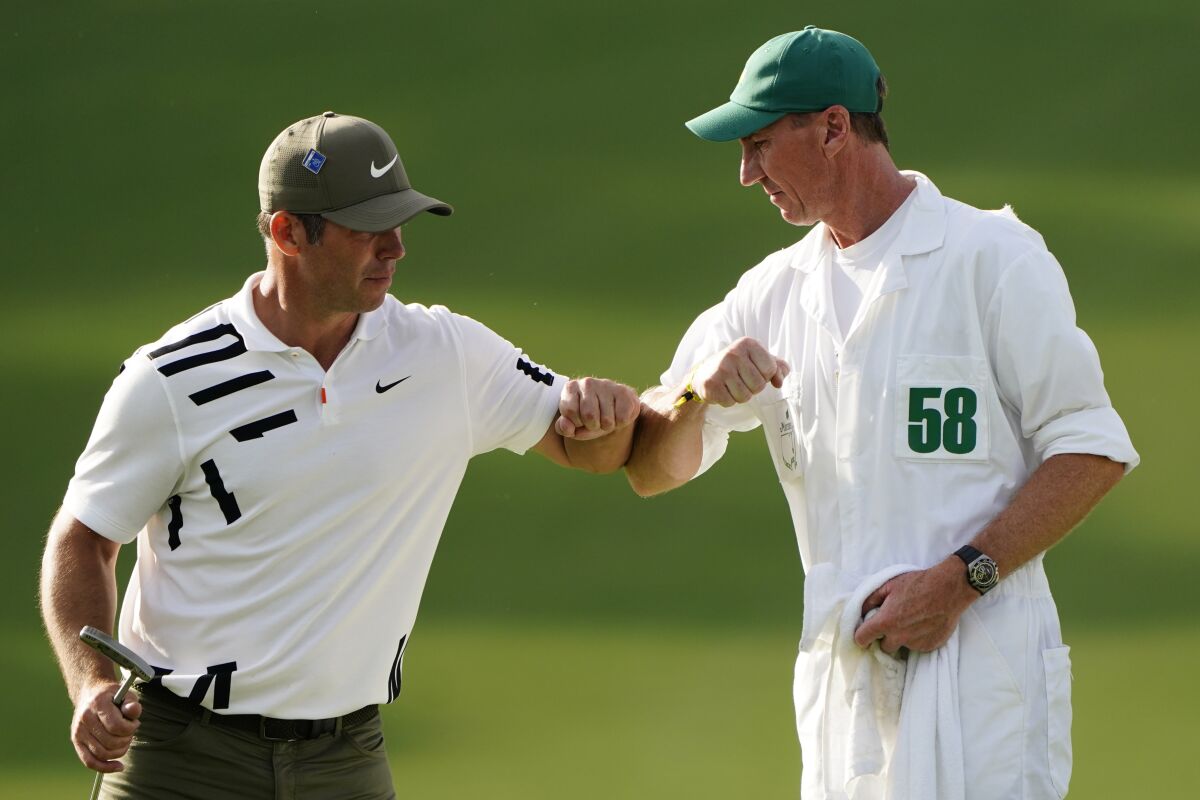 Paul Casey, of England, touches elbows with his caddie John MacLaren after his first round of the Masters golf tournament Thursday, Nov. 12, 2020, in Augusta, Ga. (AP Photo/Matt Slocum)