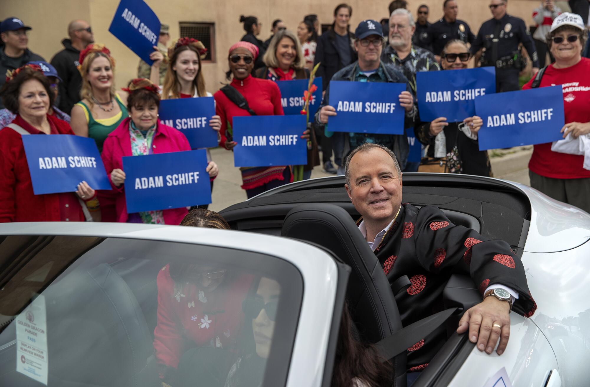   Adam Schiff monte dans un véhicule avec des supporters le long du parcours