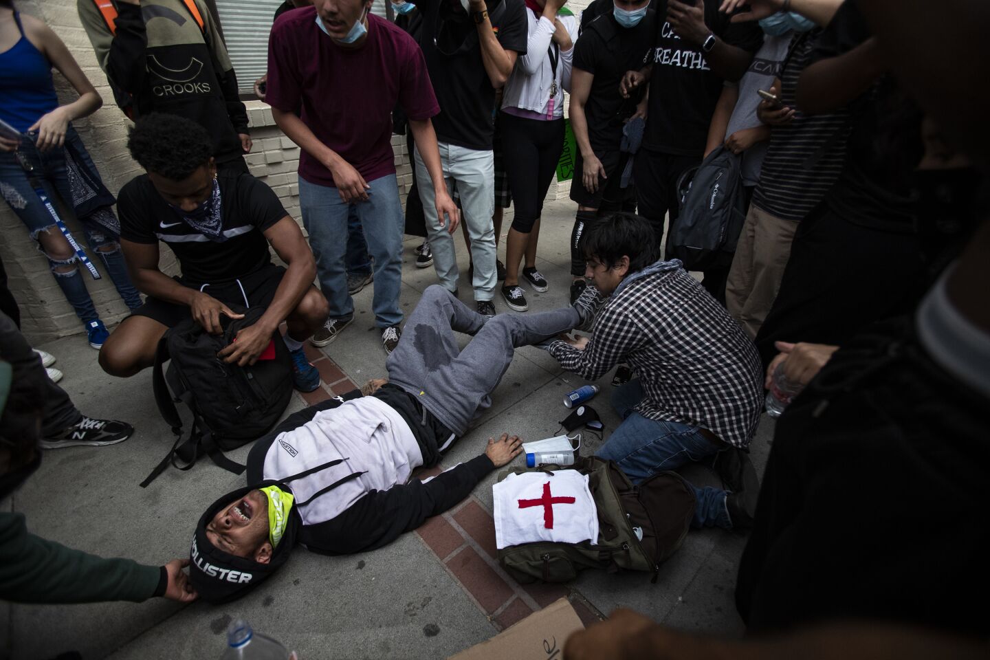 A demonstrator, injured while trying to flee nonlethal rounds, lies on the ground in Riverside.