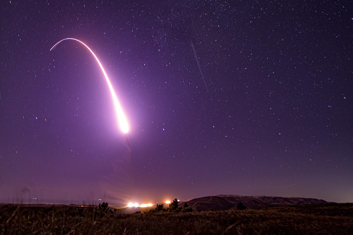 The glowing arc of a test missile launch against a starry night sky