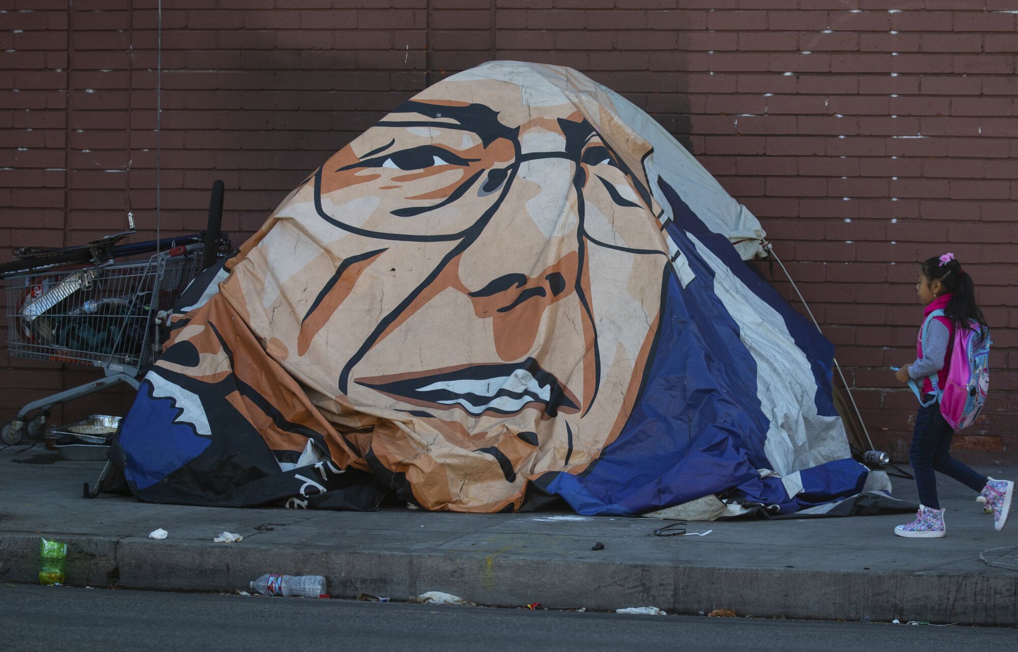 A girl walks past Leneace Pope's tent, covered with a likeness of Bernie Sanders. 