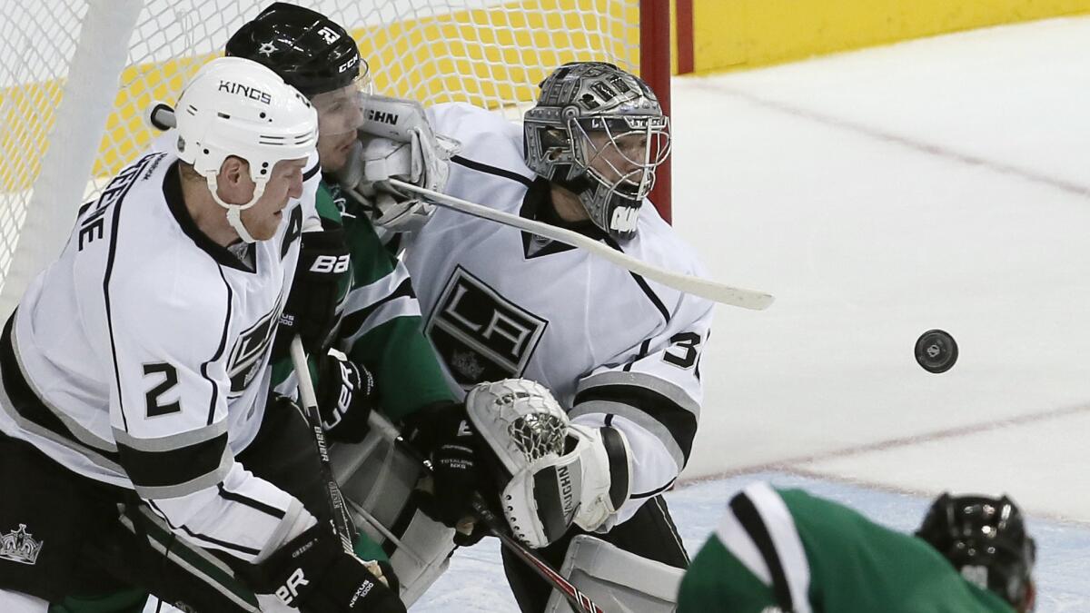 Kings goalie Jonathan Quick, center, and defenseman Matt Greene, right, battle Dallas Stars forward Antoine Roussel for a rebound during the first period of the Kings' 5-4 loss Saturday.