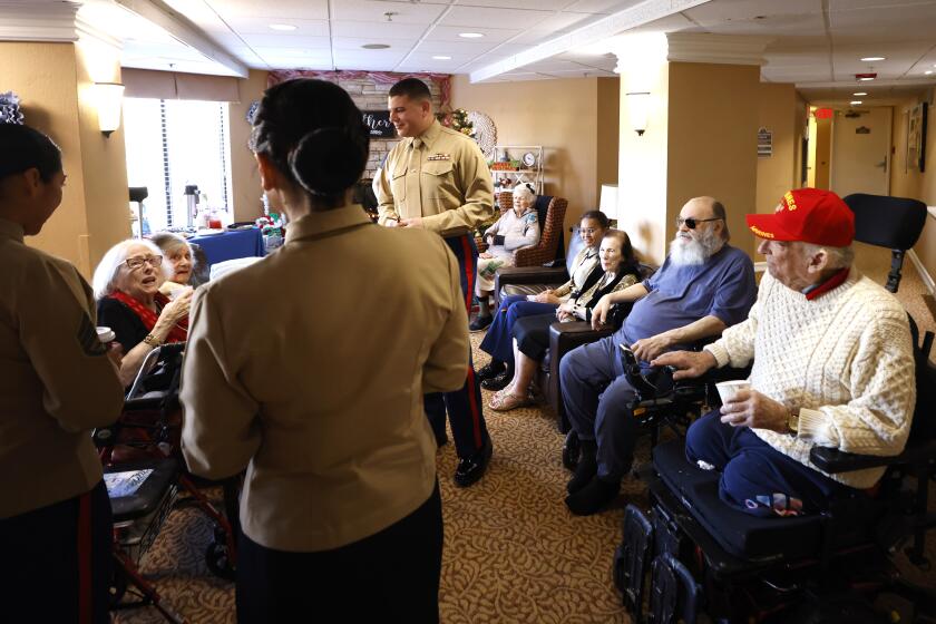 San Diego CA - December 24: 1st Lt. Jorin Hollenbeak, center, and other Marines from Camp Pendleton visited veterans and residents at Brookdale Assisted Living Facility in Oceanside on Sunday, December, 2023. Beau Evans, who served in the Marines in the Korea War, right, looks on. (K.C. Alfred / The San Diego Union-Tribune)