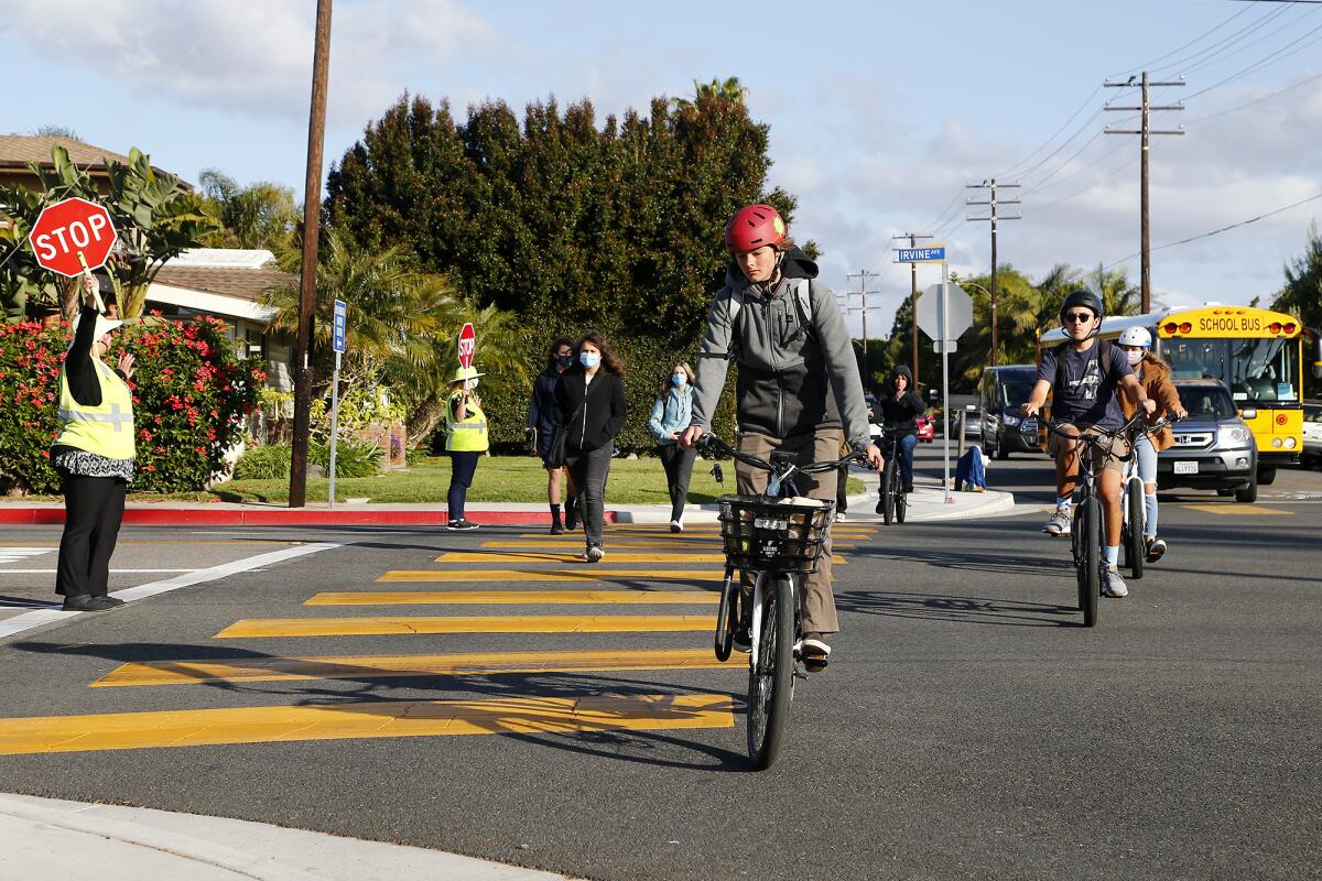Students cross Irvine Avenue along 16th Street as they return to campus for full-day learning at Newport Harbor High School.