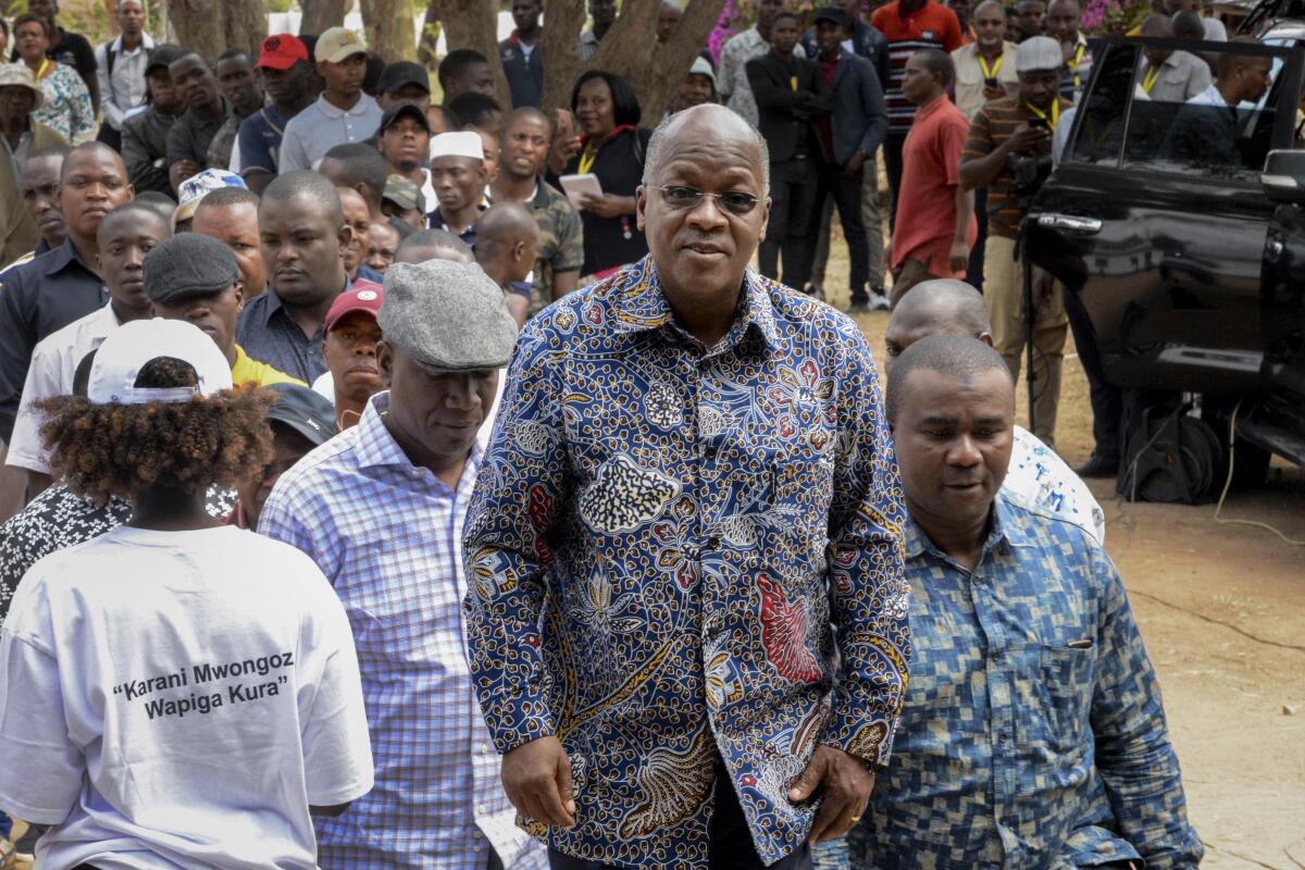 Tanzanian President John Magufuli waits in line with other people