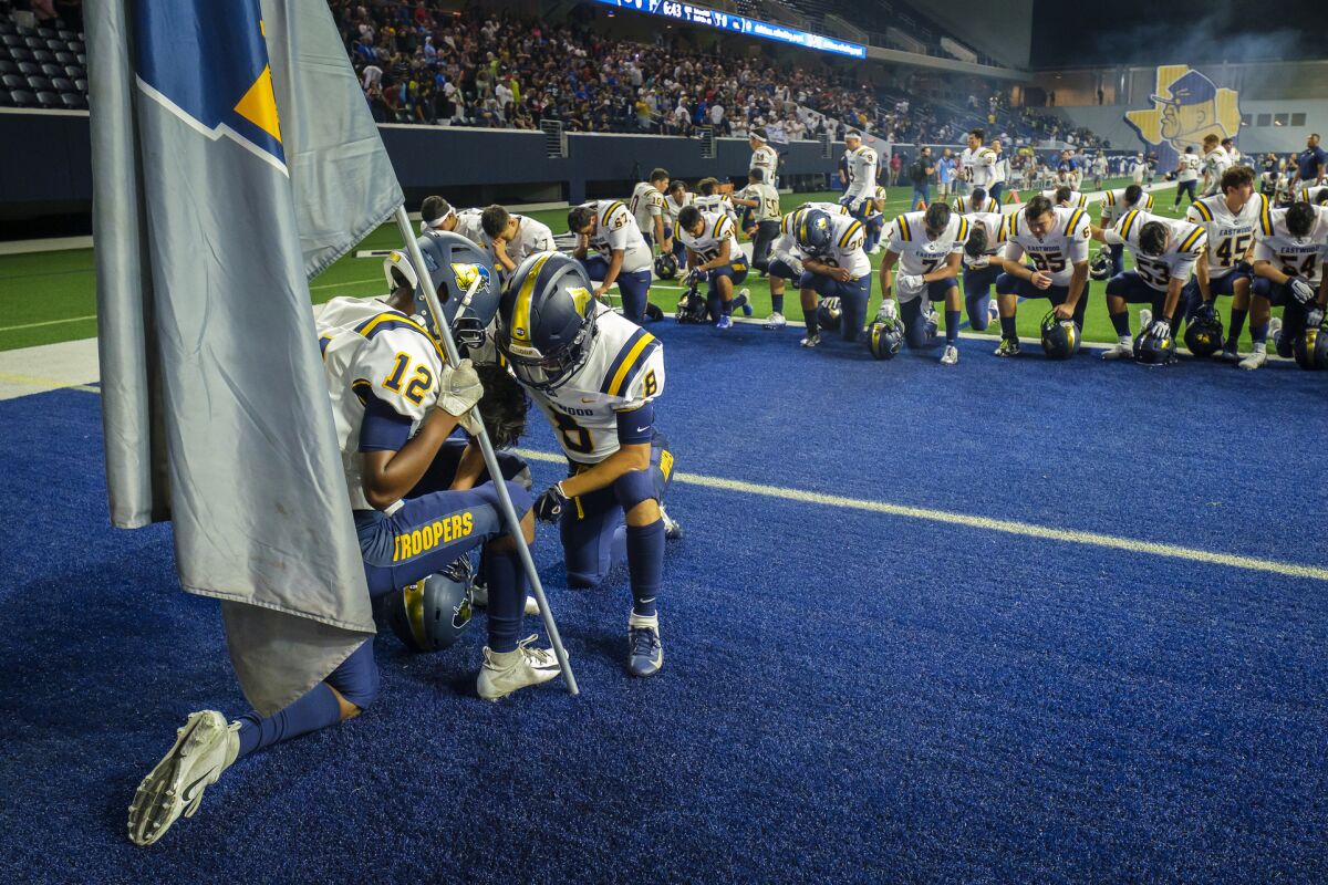El Paso Eastwood players kneel in prayer before a high school football game against Plano on Sept. 5 in Frisco, Texas.