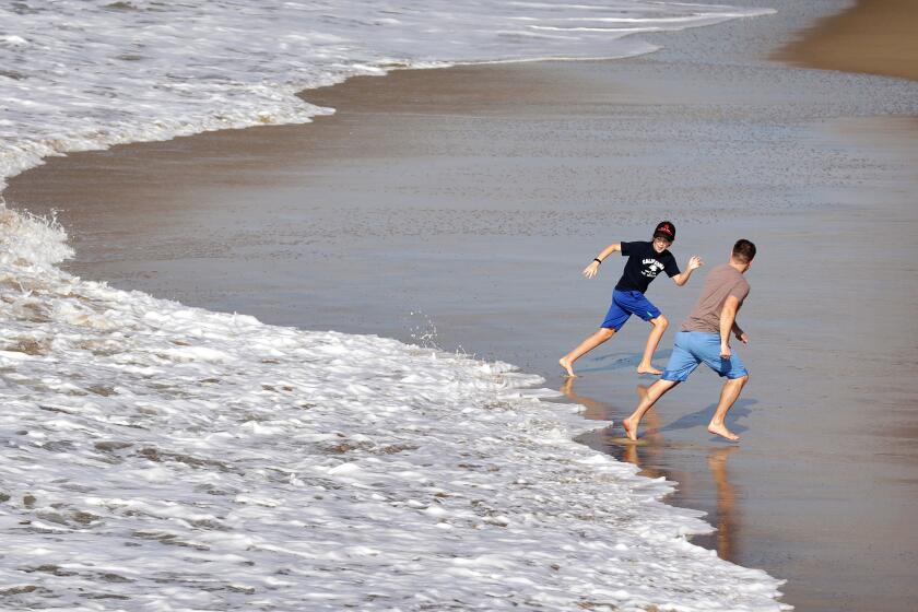 MANHATTAN BEACH-CA-DECEMBER 28, 2022: Beach goers play in the water during a break from the rain in Manhattan Beach on Wednesday, December 28, 2022. (Christina House / Los Angeles Times)