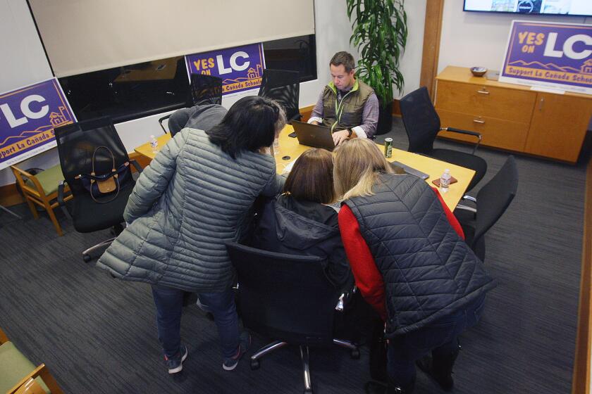 Telephone volunteers gather around a computer to get coordinated for phone calls to register local voters for Measure LC at Compass Realty in La Canada Flintridge on Thursday, January 16, 2020. The measure, which is on the next ballot, continues funding for the La Canada Unified School District which will expire if the funding is not approved by voters setting the school district back over $2 million.