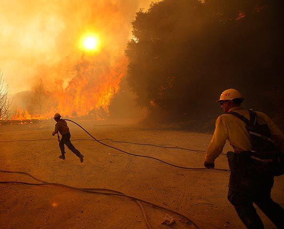 U.S. Forest Service firefighters race to battle the Station fire as it jumps Angeles Crest Highway in the Angeles National Forest. The blaze spread Thursday as canyon winds whipped flames into dry brush.