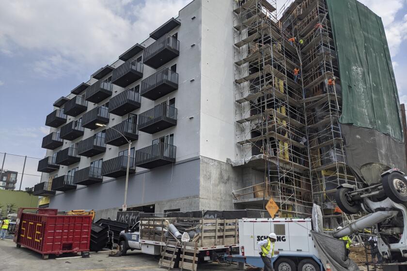 In this June 18, 2021, photo, construction workers finish the exterior of an apartment building downtown Los Angeles. California Gov. Gavin Newsom on Thursday, Sept. 16, 2021, approved two measures to slice through local zoning ordinances as the most populous state struggles with soaring home prices, an affordable housing shortage and stubborn homelessness. Newsom also signed a bill extending a 2019 law designed to make it easier to build more housing throughout the state. (AP Photo/Damian Dovarganes)