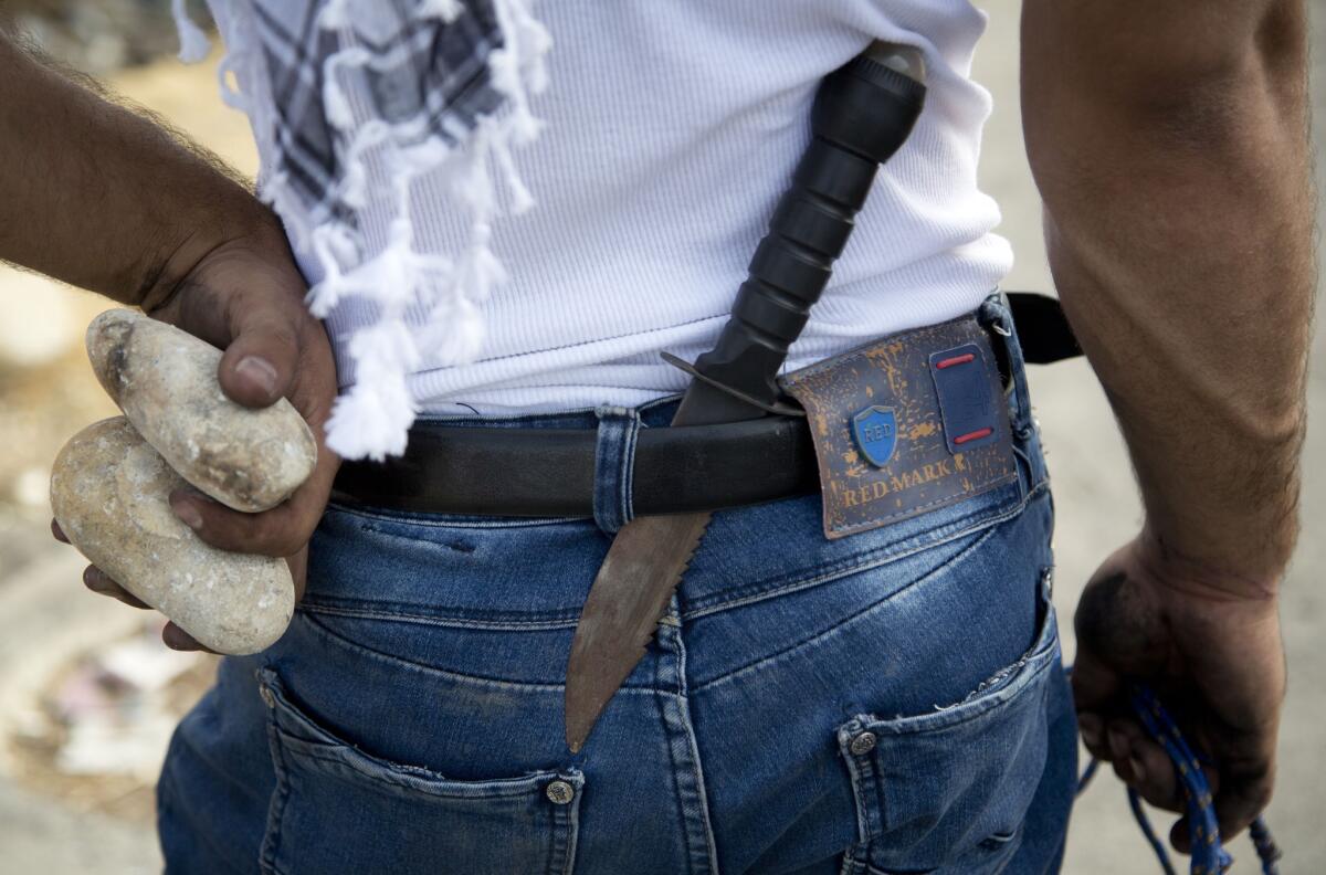 A Palestinian demonstrator has a knife in his belt and rocks in his hand during clashes with Israeli troops, near Ramallah, West Bank, on Sunday.
