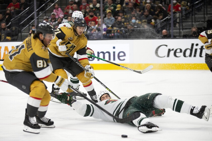 Vegas Golden Knights center Jonathan Marchessault (81) skates to make a shot on goal while center William Karlsson, behind, looks on and Minnesota Wild defenseman Jordie Benn (8) falls to the ice during the second period of an NHL hockey game Sunday, Dec. 12, 2021, in Las Vegas. (AP Photo/Ellen Schmidt)