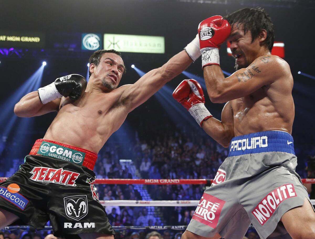 Juan Manuel Marquez lands a left jab against Manny Pacquiao in their welterweight fight in Las Vegas in December. Marquez's upcoming fight against Timothy Bradley, now set for Oct. 12, pits the last two men to beat Pacquiao -- Marquez by knockout and Bradley by dubious decision last summer.