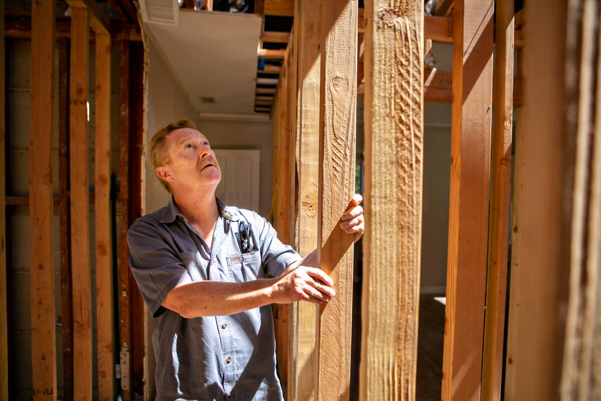 A man holds a 2-by-4 stud that is part of the framing of a building project