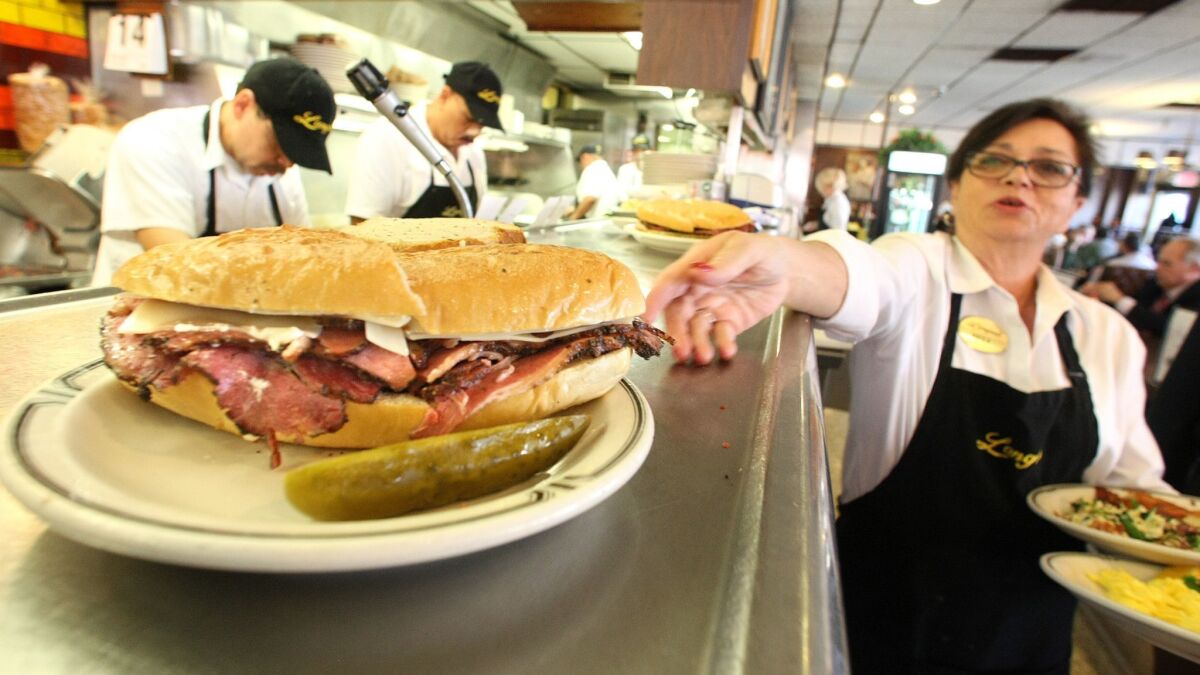 Sheila Abramson, a waitress at Langer's Delicatessen on Alvarado Street in Los Angeles, reaches for a plate containing a pastrami sandwich in 2013.