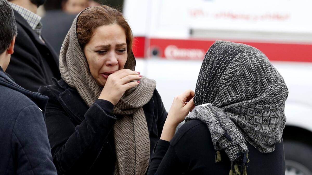 Relatives of passengers aboard Aseman Airlines Flight 3704, which crashed in the mountains of southern Iran, react outside a mosque near Tehran's Mehrabad International Airport on Feb. 18.