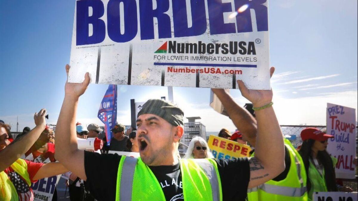 About 30 people attend an America First rally Saturday on the Camino de la Plaza Bridge near the San Ysidro border crossing, supporting President Trump and the building of his proposed border wall.